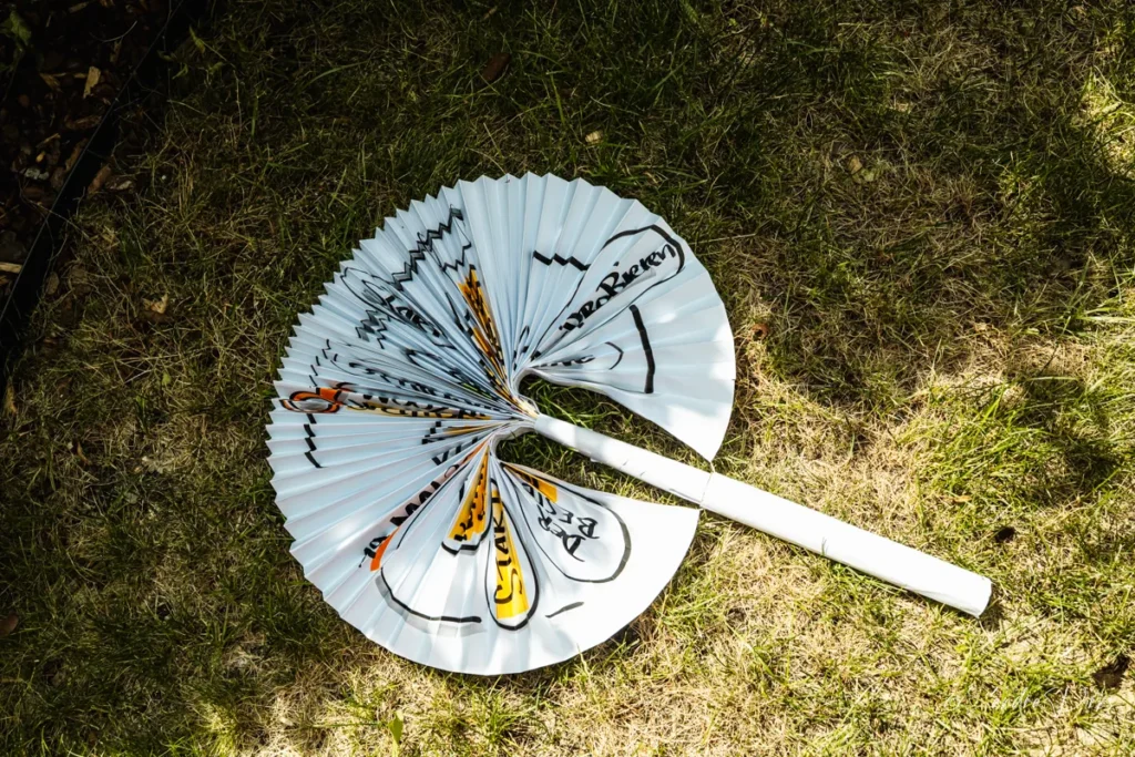 Halb geoeffneter Sonnenschirm aus einem gefalteten Flipchart mit schwarz-gelber Workshop-Beschriftung, auf der Wiese liegend