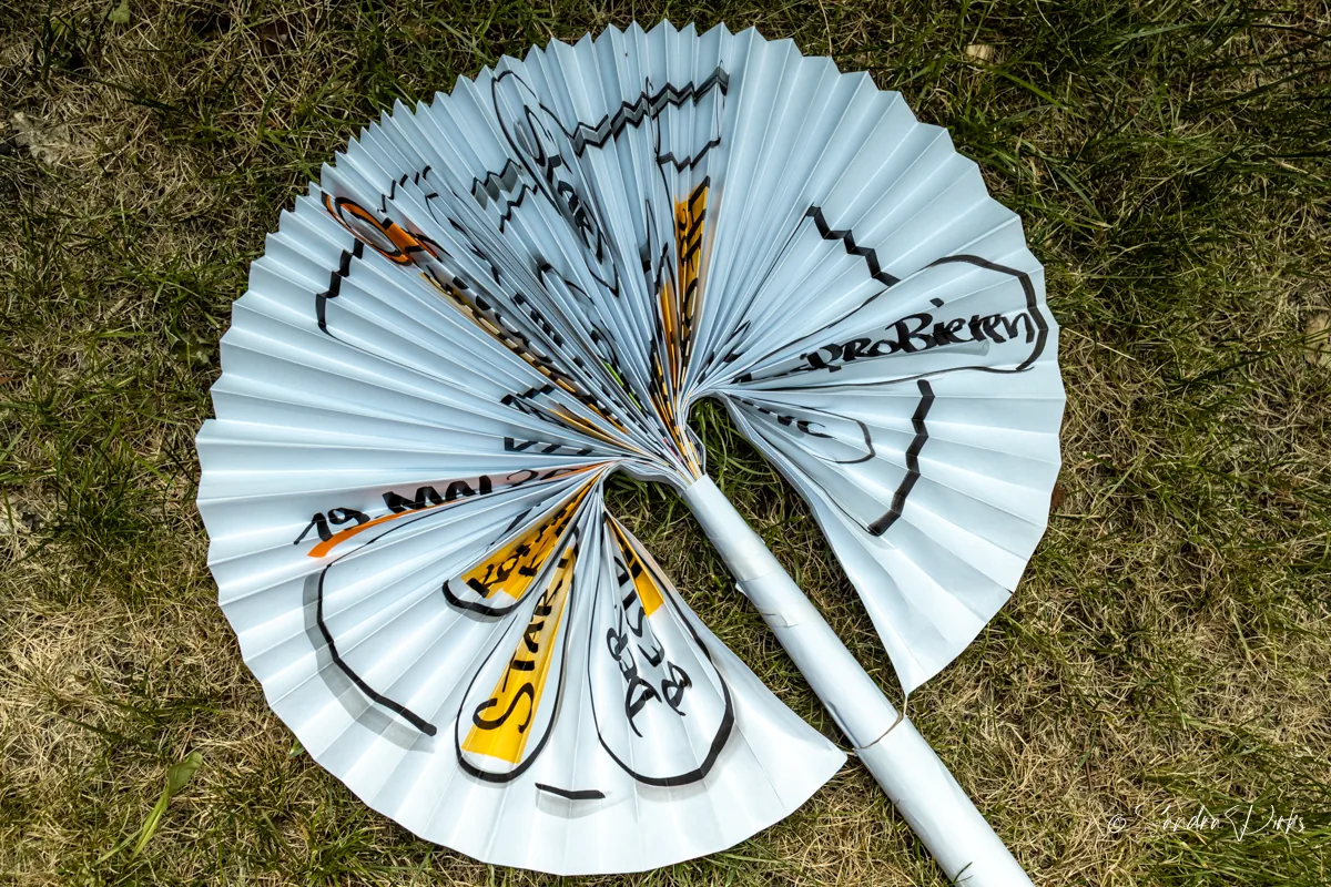 Aufgefaecherter Flipchart-Sonnenschirm mit Stiel aus zusammengerolltem Papier auf dem Rasen