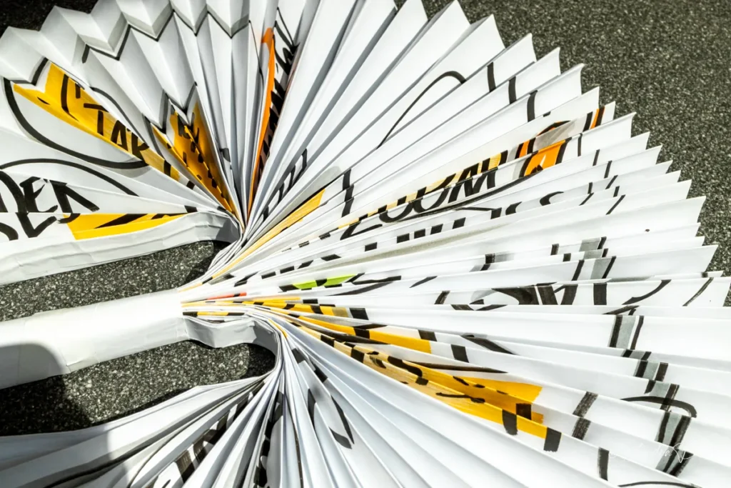 Dicht gefalteter Flipchart-Faecher in der Nahaufnahme - zwischen den Falten blitzt die Marker-Beschriftung hervor