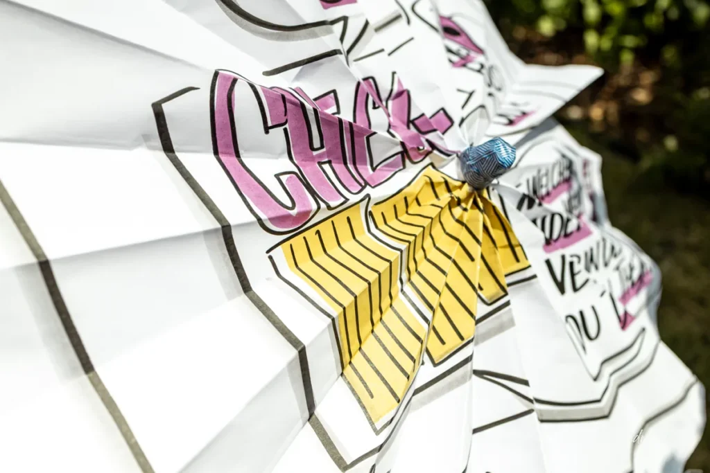 Zentrum des gefalteten Check-in-Flipcharts mit pinkem Check-in-Schriftzug und gelbem Farbfeld