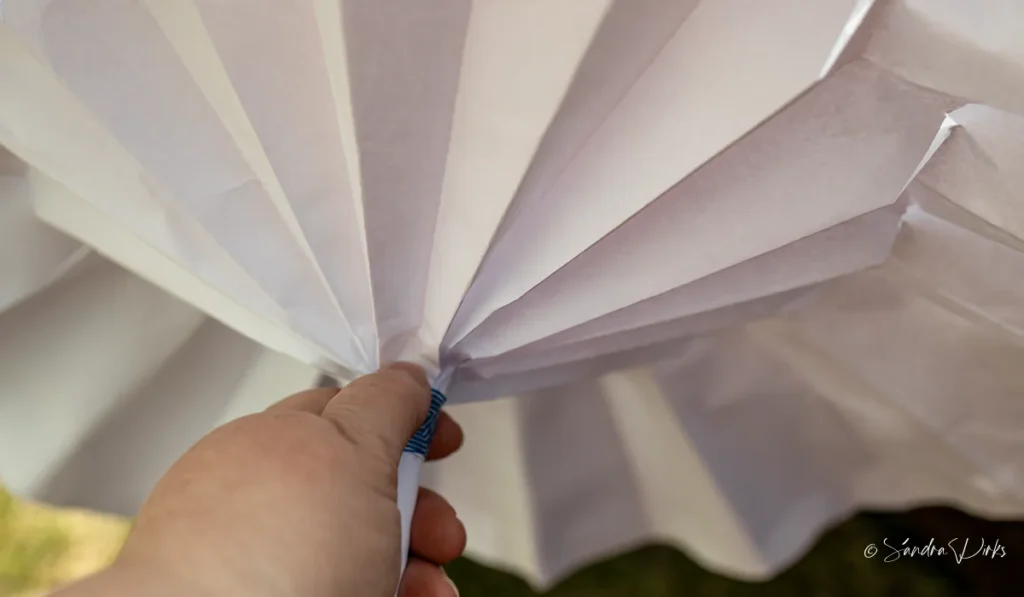 Eine Hand haelt den Flipchart-Sonnenschirm am Griff - Blick von unten in die weissen Falten