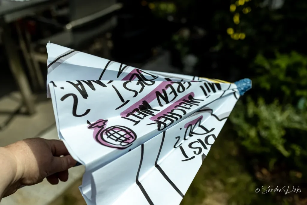 Der zusammengefaltete Flipchart-Schirm sieht aus wie ein grosser Papierflieger und wird in der Hand gehalten