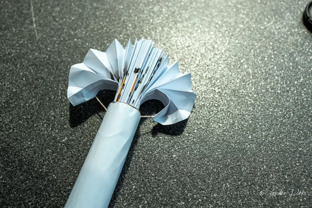 Kleiner, halb geoeffneter Flipchart-Faecher mit Papierrollen-Griff auf dunklem Boden