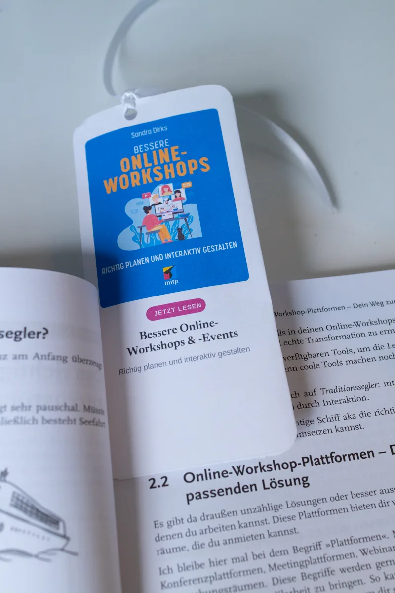 Lesezeichen hängt mit weißem Bändchen im aufgeschlagenen Buch Bessere Online-Workshops
