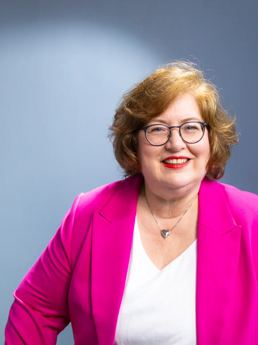 Sandra Dirks im pinken Blazer, die Hände in die Hüften gestützt